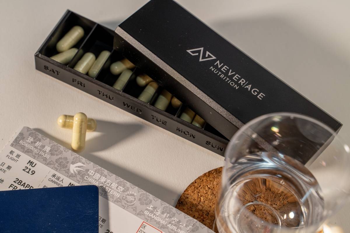 Never Age Pillendose neben Bordkarte und Reisepass